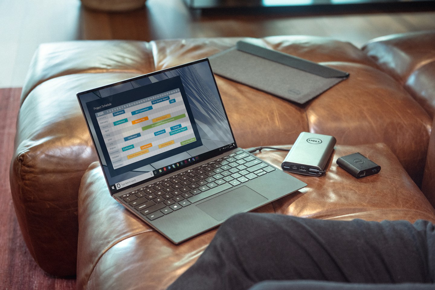 Laptop with project schedule on a brown leather sofa.